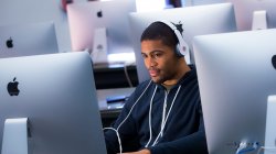 Student wearing headphones while using large-screen computer in computer lab