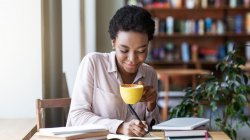 Person writing a story with a cup of coffee in their hand.